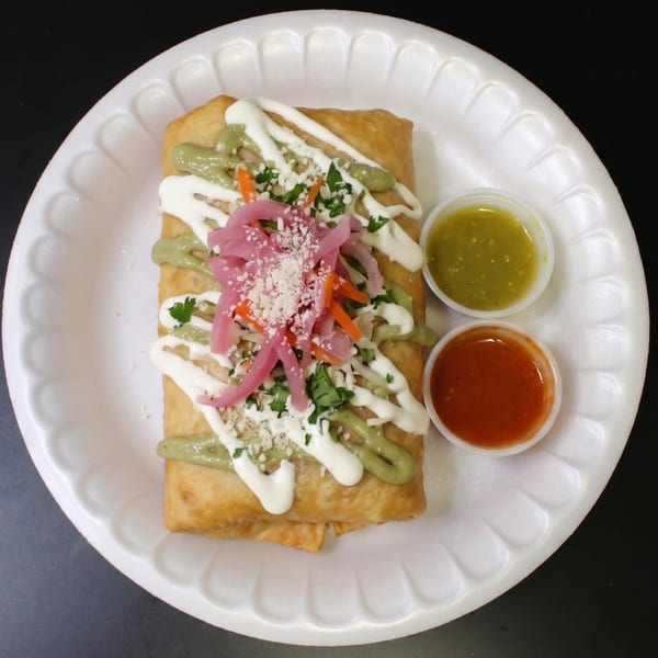 Deep-fried burrito topped with green and white sauces, pickled onions, and two sides of salsa.