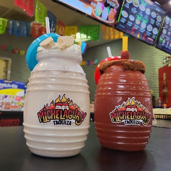 Two Michelaguas drinks, one white and one red, with festive decorations in the background.